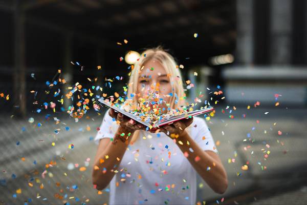 Quelle: pixabay.com / Paul_Stachowiak, https://pixabay.com/de/photos/frau-konfetti-funkelt-blondine-6318447/ Frau hält Buch mit fliegendem Konfetti